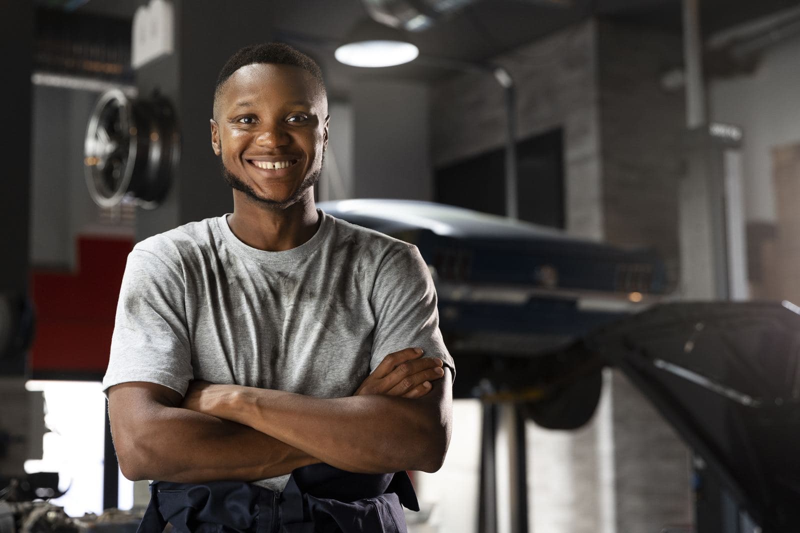 Automotive technician standing in a workshop with a car on a lift